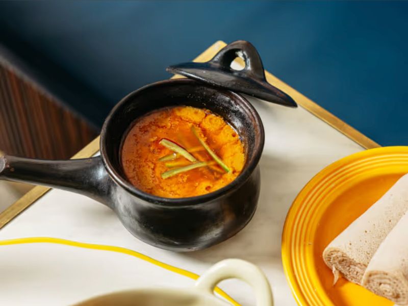 Shiro simmered in a traditional black clay pot with rolled injera