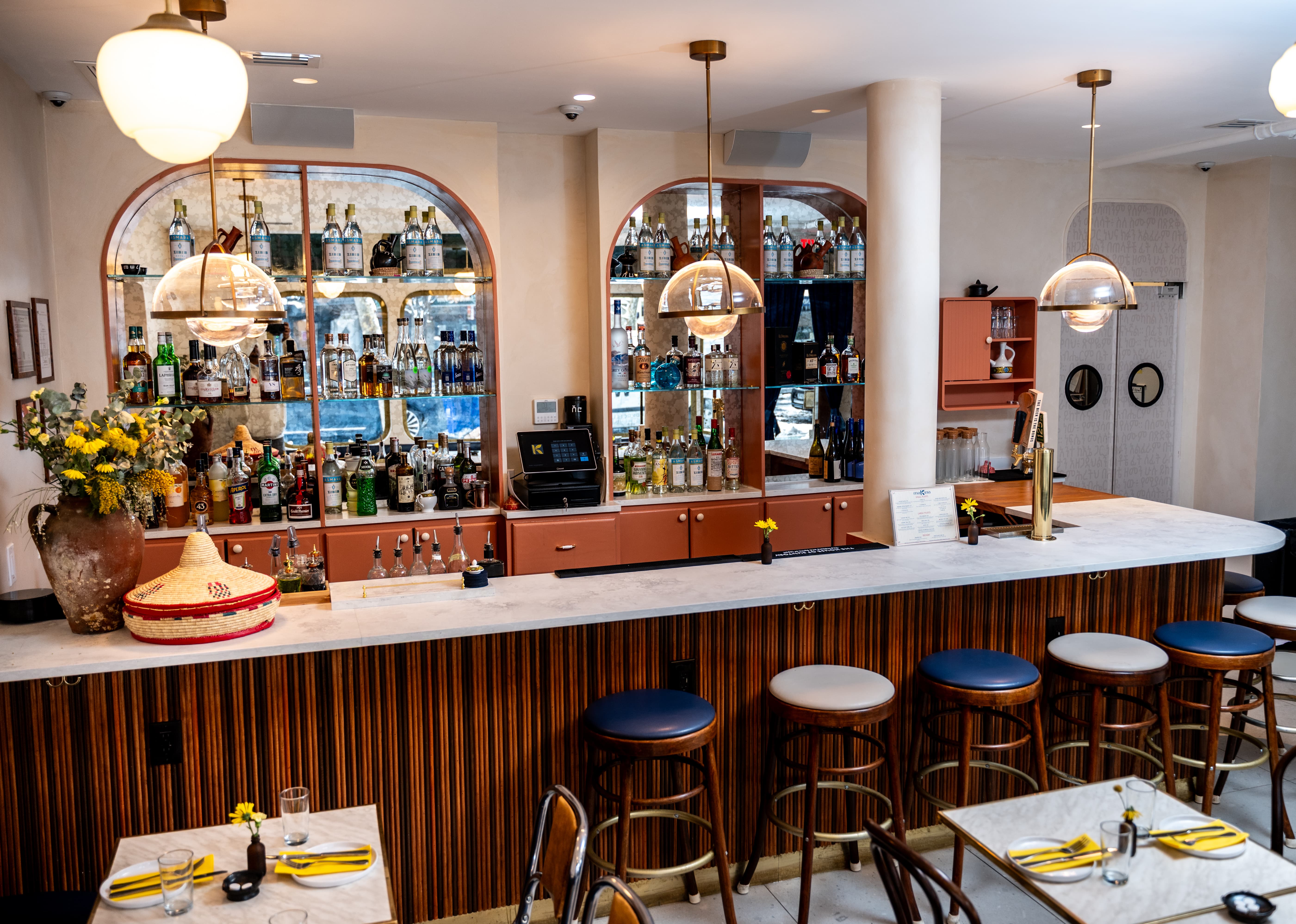 Makina bar counter with bottles on shelves and warm ambient lighting